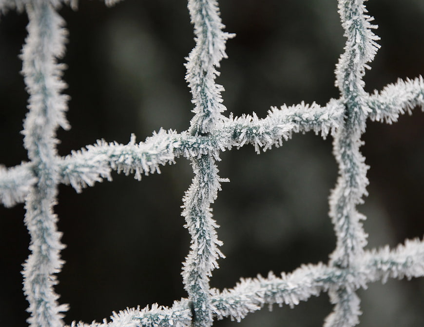Close-up of frost-covered wire fence in winter