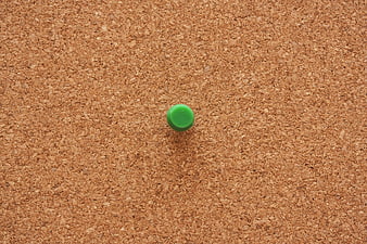 Green Push Pin on Textured Cork Board Background