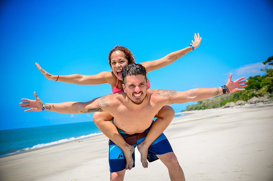 Happy couple piggyback ride on sunny tropical beach