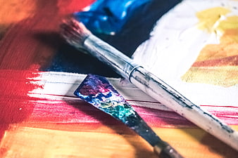 Close-up of paintbrush and palette knife on colorful canvas