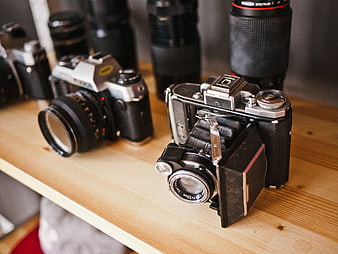 Vintage folding camera and film equipment on wooden shelf