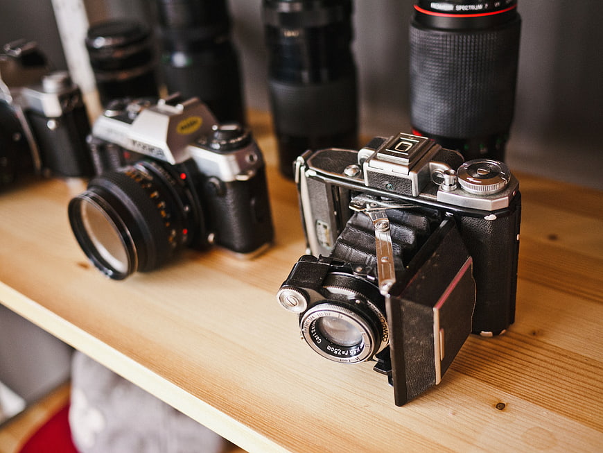 Vintage folding camera and film equipment on wooden shelf