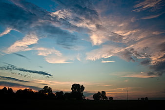 Dramatic sunset sky with clouds over silhouetted trees
