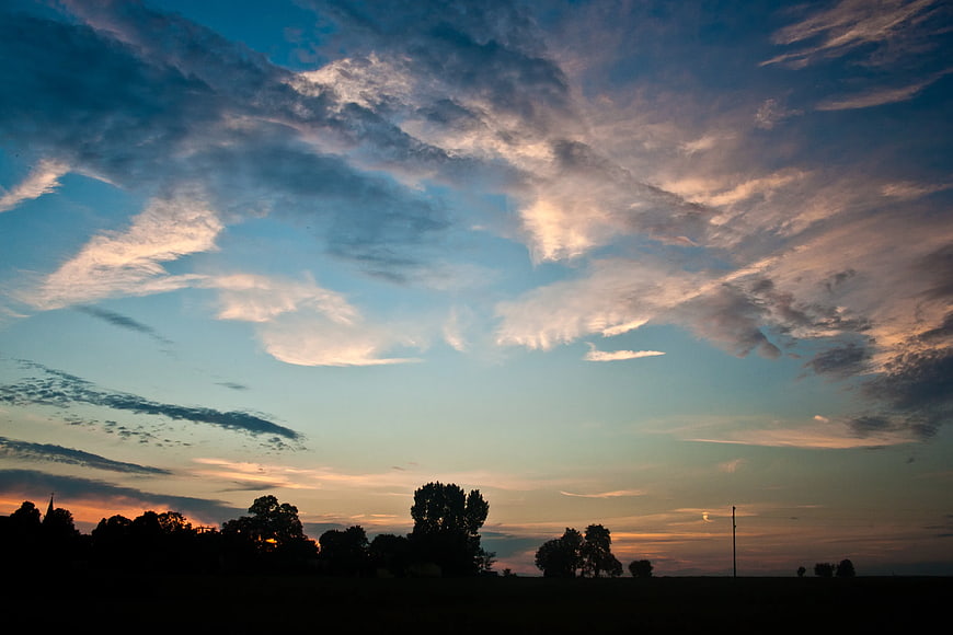 Dramatic sunset sky with clouds over silhouetted trees