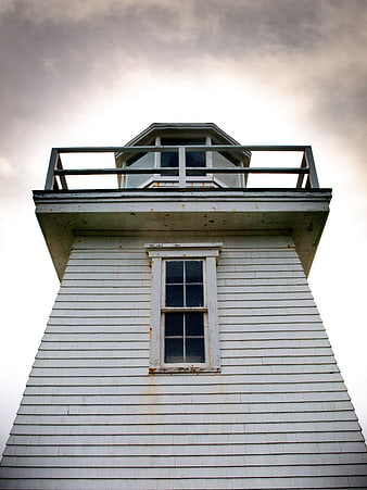 Low angle view of white lighthouse tower against cloudy sky