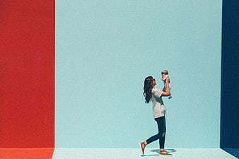 Mother holding baby against colorful geometric wall background