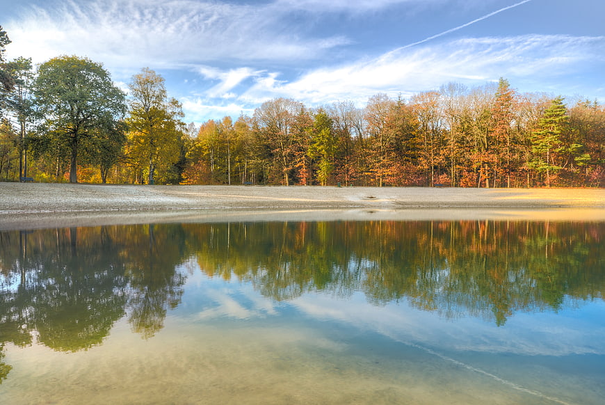 Serene Autumn Lake Reflection with Colorful Forest and Blue Sky