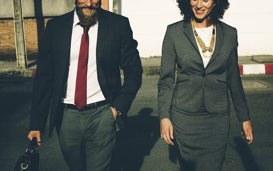 Businessman and businesswoman walking together in professional suits