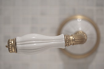 Close-up of vintage white porcelain and gold cabinet handle