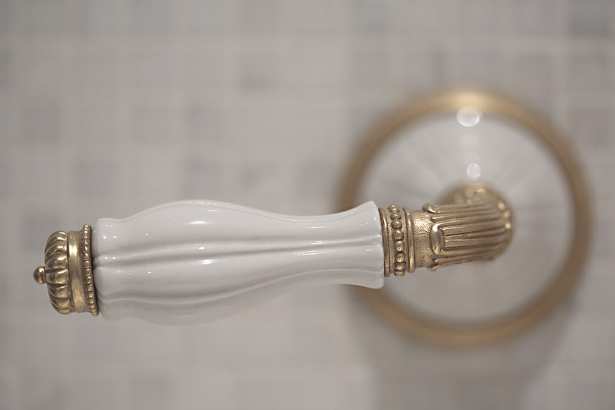 Close-up of vintage white porcelain and gold cabinet handle