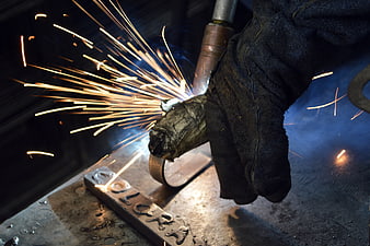 Close-up of industrial welding with bright sparks and protective gloves