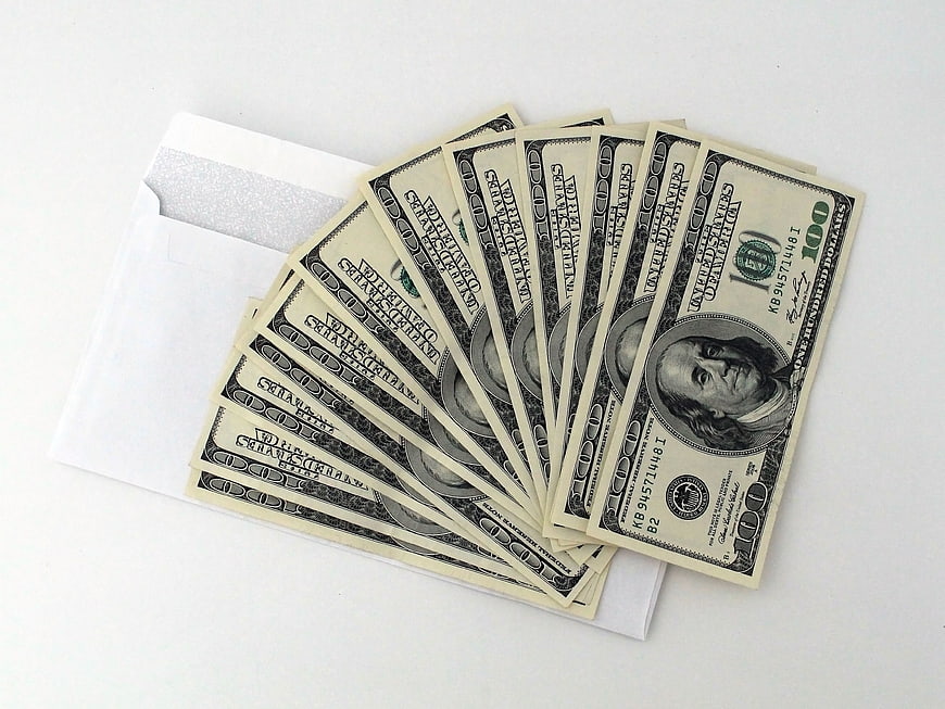 Stack of hundred dollar bills on white envelope