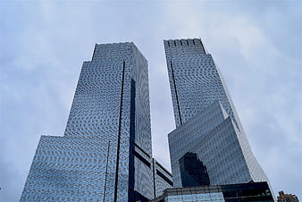 Low angle view of modern glass skyscrapers against cloudy sky