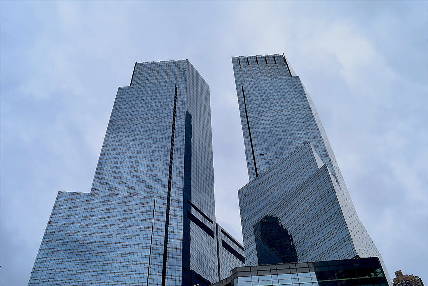 Low angle view of modern glass skyscrapers against cloudy sky