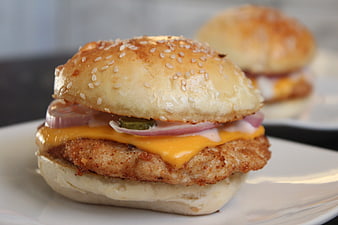 Close-up of crispy chicken burger with melted cheese and onions