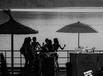 Black and white photo of friends socializing at a lakeside bar