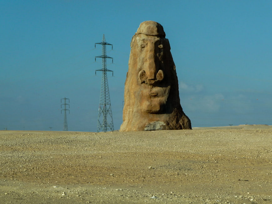 Desert Landscape with Stone Face Sculpture and Power Lines