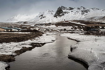 Snowy River Flowing Through Icelandic Village with Mountains