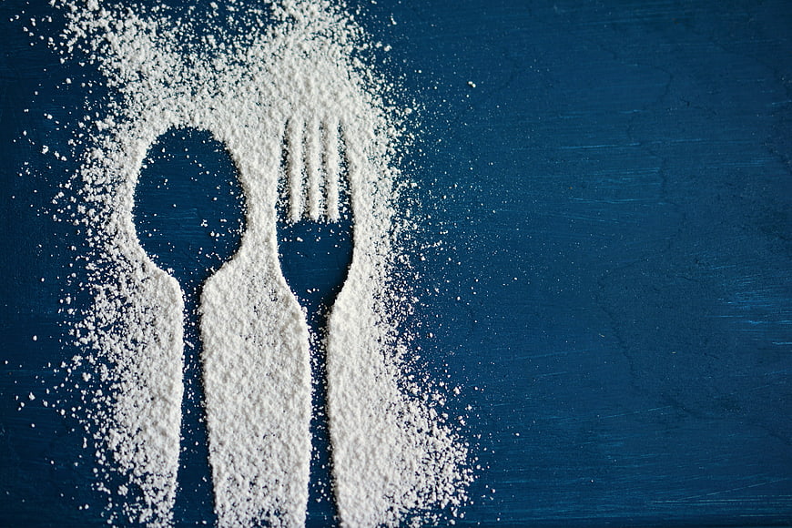 Spoon and fork silhouettes made of white powder on dark blue background