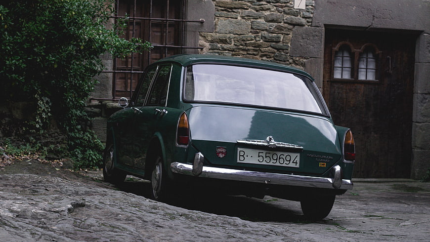 Vintage Green Car Parked on Cobblestone Street