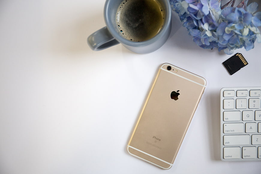 Flat lay workspace with gold smartphone, coffee, and keyboard