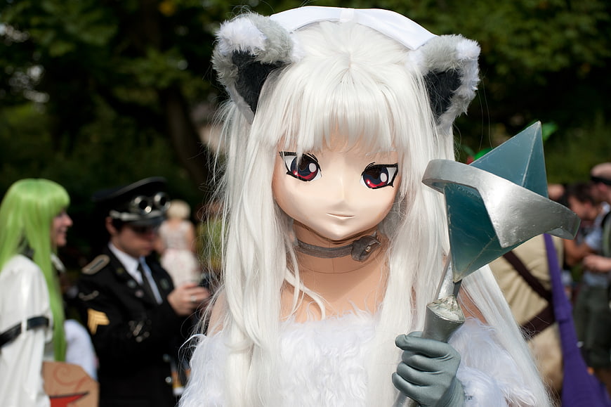 White-haired anime cosplay character with cat ears and weapon