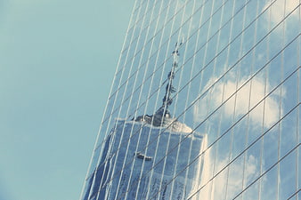 Modern Glass Skyscraper Reflecting City Skyline and Clouds