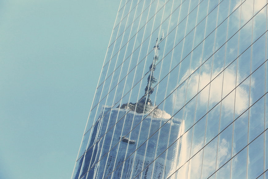 Modern Glass Skyscraper Reflecting City Skyline and Clouds