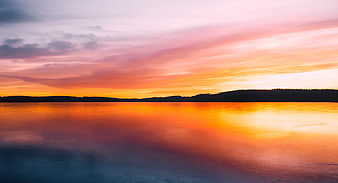 Vibrant Sunset Reflection on Frozen Lake with Forest Silhouette