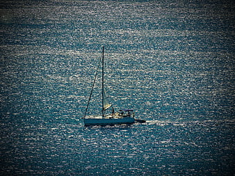 Aerial view of sailboat on shimmering blue sea