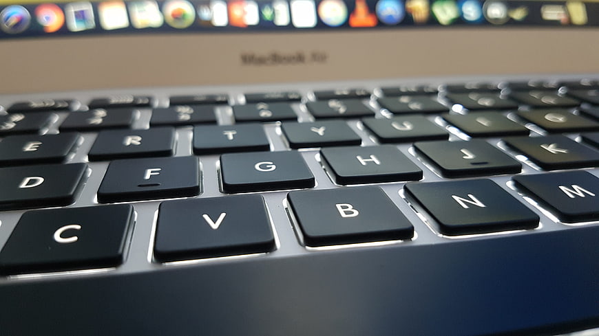 Close-up of a MacBook Pro keyboard with blurred screen background