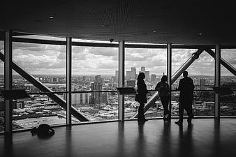 Silhouetted Business People Looking Out High-Rise Window at City Skyline