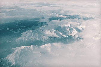 Aerial View of Snow-Capped Mountain Peaks Through Clouds