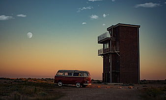 Vintage red van parked near brick tower at sunset