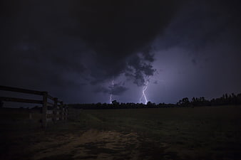 Night Lightning Strike Over Rural Field With Wooden Fence