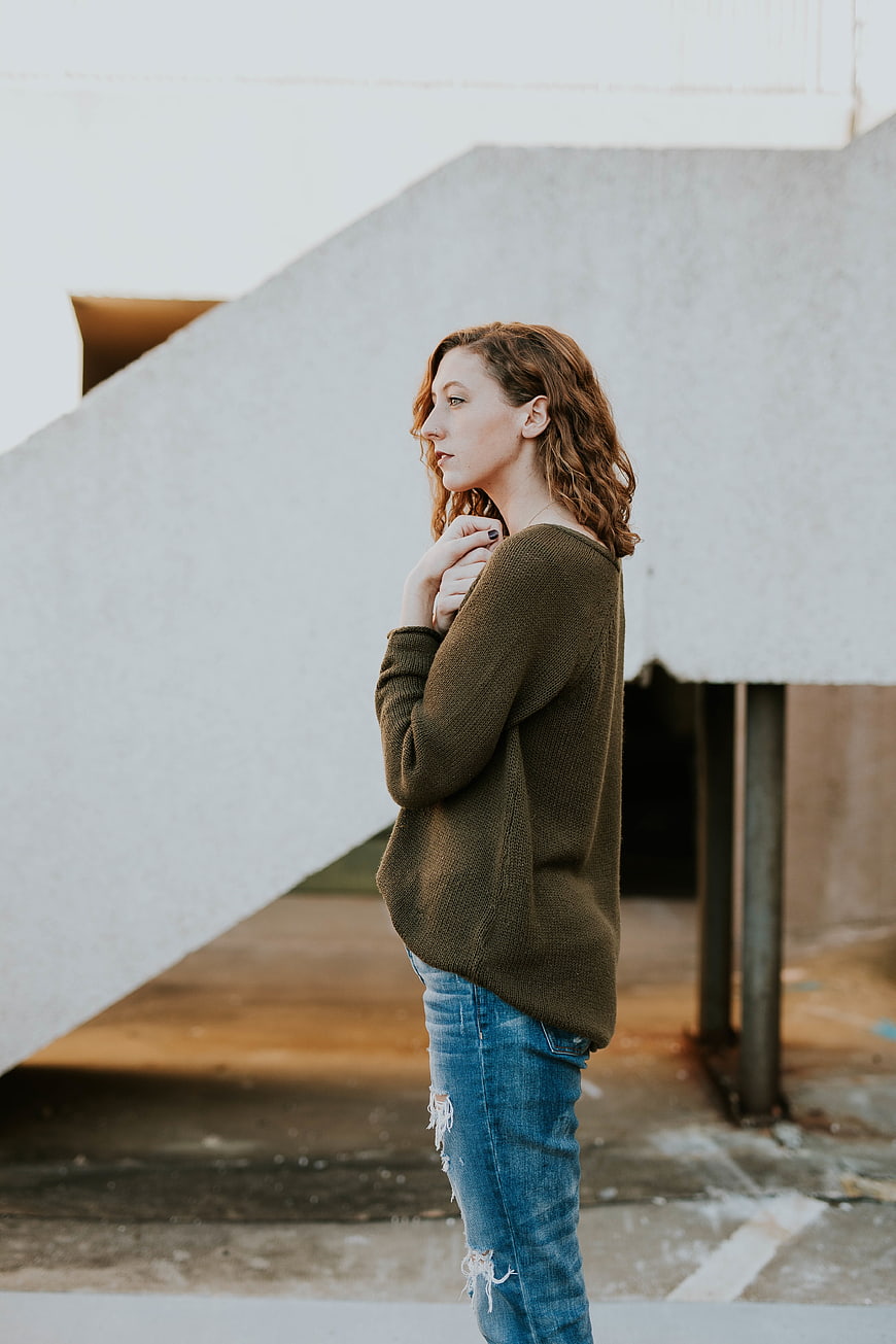 Woman in Olive Sweater and Ripped Jeans Standing Outdoors