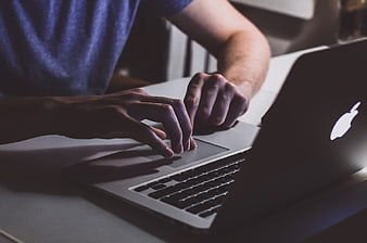 Close-up of Man Typing on Laptop in Dimly Lit Office