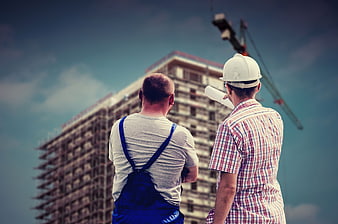 Construction workers inspecting building site with crane