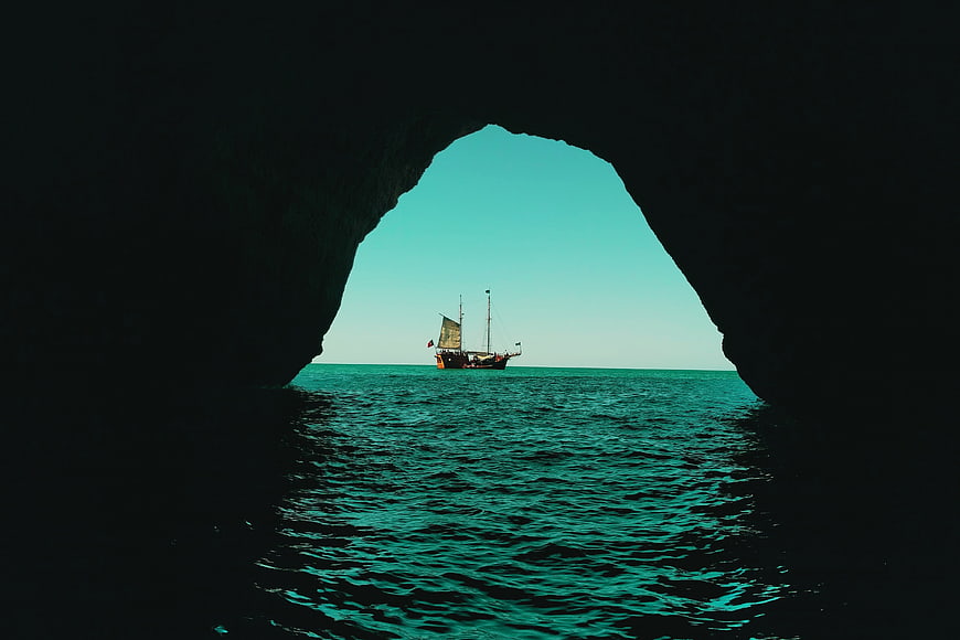 Traditional Dhow Boat Framed by Sea Cave Arch