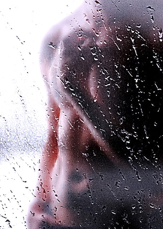 Sensual male silhouette behind rain-streaked glass