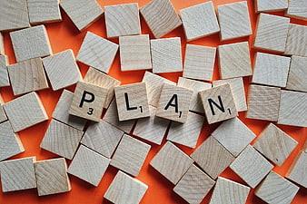 Wooden Scrabble Tiles Spelling Plan on Orange Background