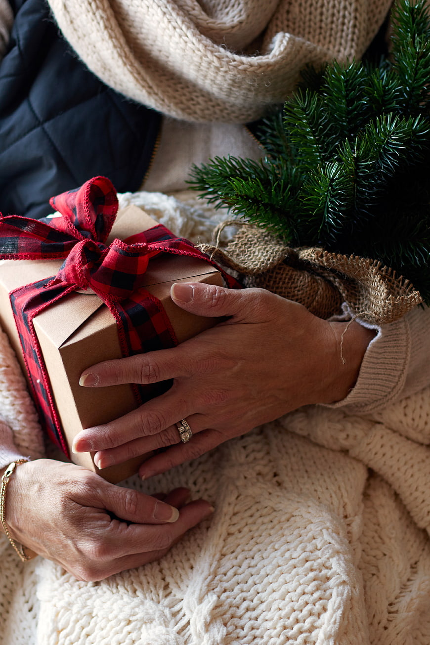 Woman holding Christmas gift box with plaid ribbon