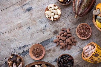 Top view of cocoa pods, cashews, and cacao nibs on rustic wood