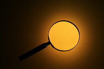 Magnifying glass silhouette against warm glowing amber background