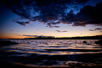 Dramatic Sunset Over Lake with Silhouetted Hills and Clouds
