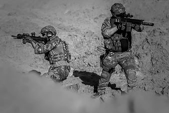 Two soldiers in tactical gear aiming rifles in black and white