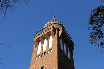 Low angle view of red brick observation tower against blue sky