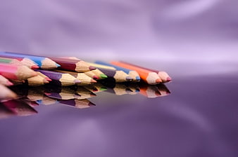 Colorful Pencils on Purple Surface with Reflection