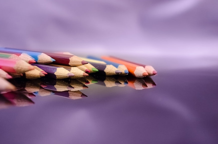 Colorful Pencils on Purple Surface with Reflection