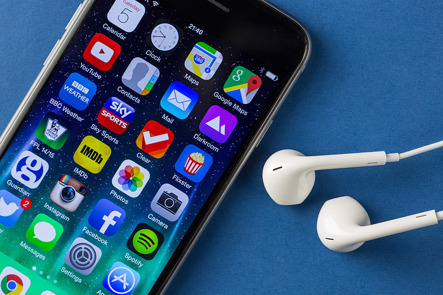 Smartphone with App Icons and White Earbuds on Blue Background